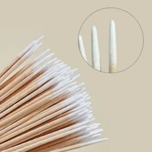 Close-up of pointed wooden cotton applicator sticks with white precision tips and detail inset on a beige background for beauty treatments.