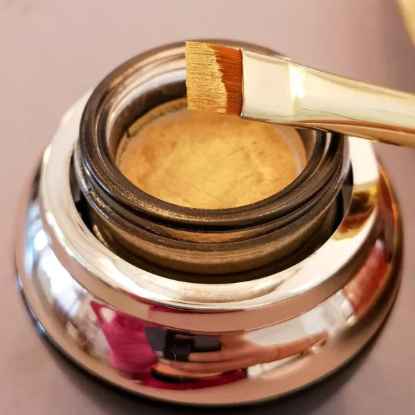 Open jar of Nikk Mole Glossy Gold Brow Paste, with a shimmering golden formula for eyebrow contouring