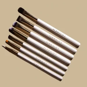 Permalift Brow & Lash Brushes Master Kit featuring eight professional brushes with white handles and gold ferrules, arranged diagonally on a beige background