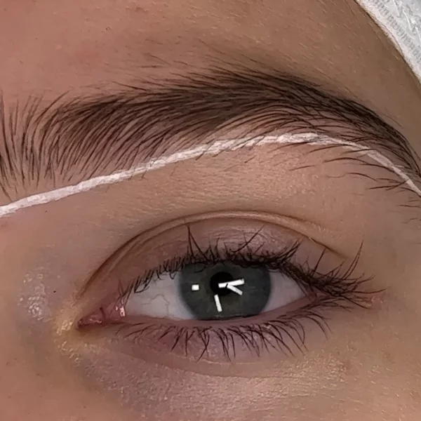 Close-up of a client's eye with a white brow mapping line drawn above the eyebrow, showcasing precise brow shaping using a Permalift brow mapping pen