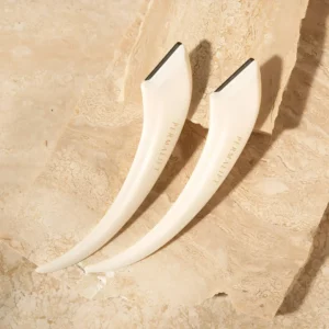 Permalift duo eyebrow razors with sleek white handles and fine blades, elegantly styled on a beige stone background for brow shaping precision