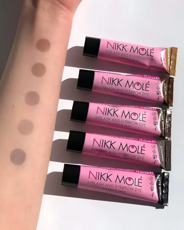 Nikk Mole Eyelash and Eyebrow Dye in five shades, shown as swatches on an arm, demonstrating the color range and pigment intensity from light to dark brown hues