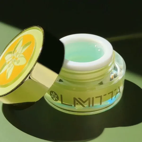 Lamitta Honey Glue in a luxurious glass jar with a golden lid, opened to reveal its smooth, translucent formula under natural sunlight